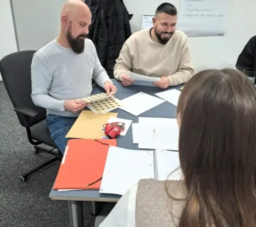 Teilnehmende im AdA Kurs in Kassel arbeiten gemeinsam an Unterlagen im Seminarraum