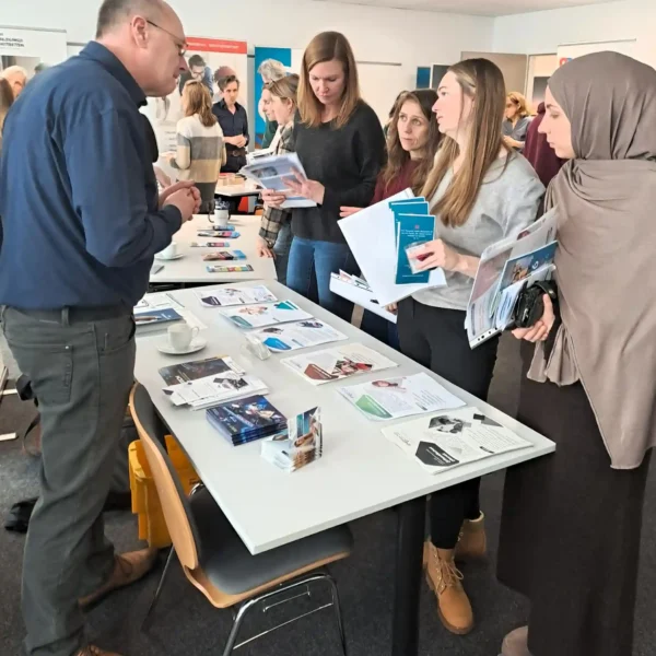 AVGS Veranstaltung im Jobcenter Kassel: EMBRAND Stand mit Informationsmaterial zu AVGS Coaching und IT Coaching im Gespräch mit Teilnehmenden