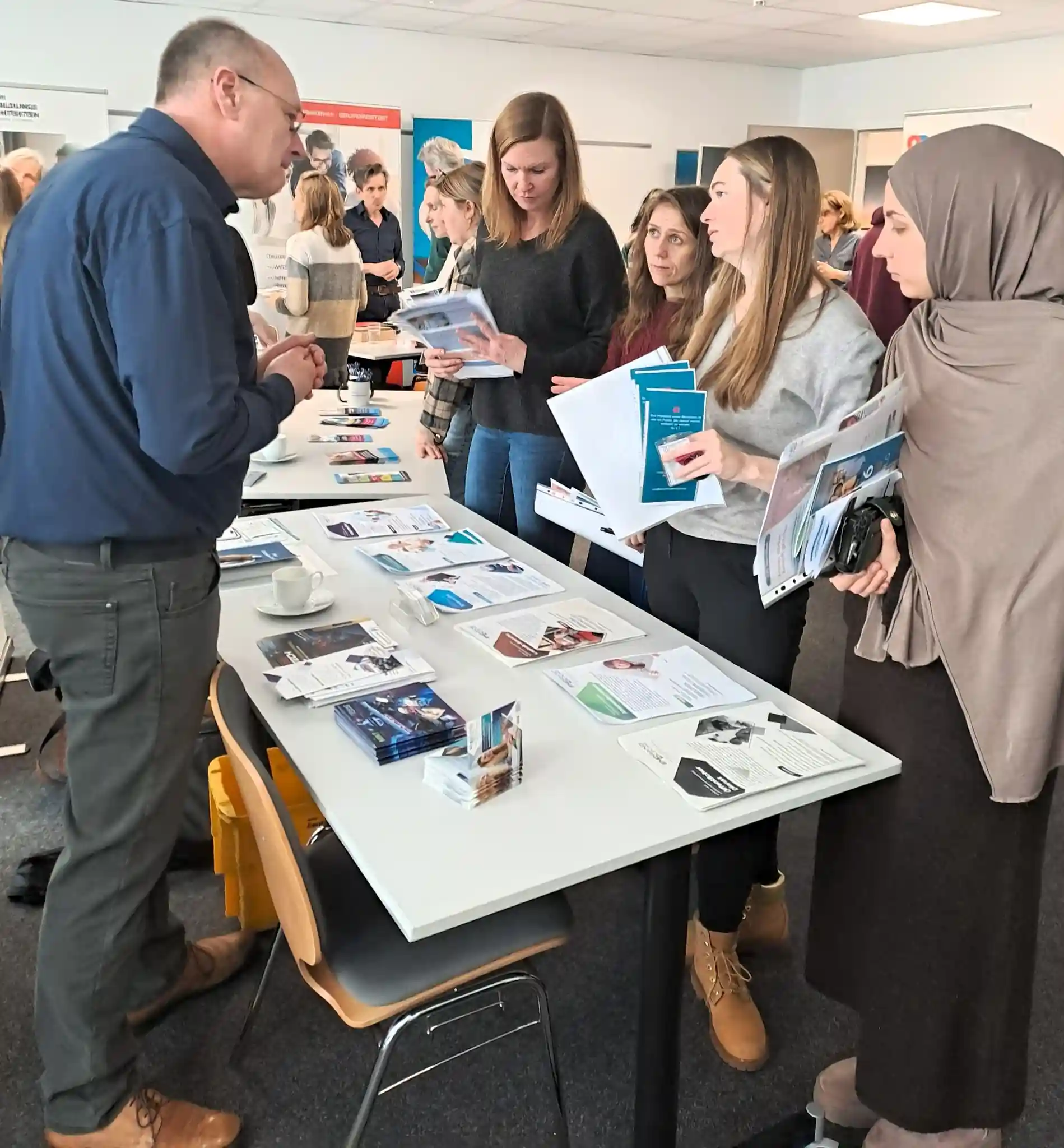 AVGS Veranstaltung im Jobcenter Kassel: EMBRAND Stand mit Informationsmaterial zu AVGS Coaching und IT Coaching im Gespräch mit Teilnehmenden